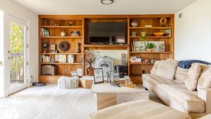 A living room with a sofa, coffee table, and a TV mounted on a wooden wall. - Huge 2Br/2Ba Unit w/Pvt Deck + 5 min to Ocean (Richmond)
