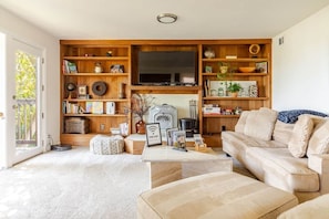 A living room with a sofa, coffee table, and a TV mounted on a wooden wall.
