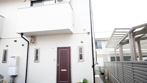 A white building with a red door, an air conditioning unit, and a small window. - Miraie Yokkaichi Hinaganishi (Yokkaichi)