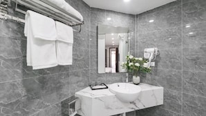 A modern bathroom with a marble sink, a towel rack with two towels, a mirror, and a hairdryer on the wall. - Charming Moon Hotel (Hanoi)
