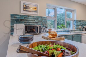 A kitchen with a microwave, a bowl of salad, and a loaf of bread on the counter. - The Paddocks 4 bedroom home (County Kerry)