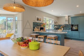 Une cuisine moderne dotée d’un grand îlot central, de chaises en bois et d’une table à manger agrémentée de produits frais.