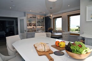Une cuisine moderne dotée d’un grand îlot central, de meubles blancs et offrant une vue sur l’extérieur.