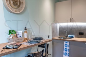 Een moderne keuken met een houten aanrecht, roestvrijstalen apparatuur en een decoratieve wandklok.