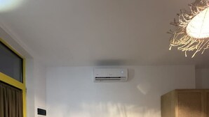 A living room with a sofa, a small stool, and a wardrobe. - Noon Properties 1 Beachside 1BR in Dh rmi (Himarë)