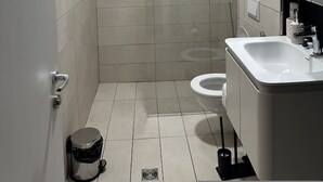 A modern bathroom with a shower, toilet, and sink. - Noon Properties 1 Beachside 1BR in Dh rmi (Himarë)