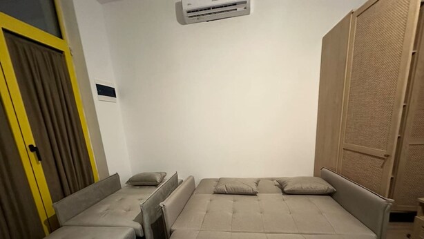 A bedroom with a bed, two bedside tables, a wardrobe, and an air conditioning unit. - Noon Properties 1 Beachside 1BR in Dh rmi (Himarë)