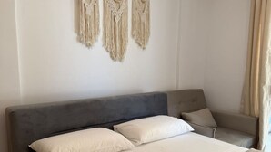 Un dormitorio con una cama grande, un cabecero gris y un tapiz de macramé en la pared.