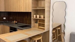 Una cocina moderna con armarios de madera, encimera negra y una barra integrada con taburetes.