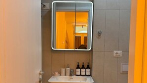 Un baño con lavamanos blanco, un espejo y un inodoro.