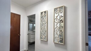 Un passadís amb una porta de fusta, una paret blanca i dos panells decoratius.