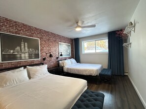 A hotel room with two beds, a brick wall, a ceiling fan, and a window with curtains. - Stampede |BMO | Stanley Park | Sleeps 6 (Calgary)
