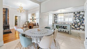 A spacious dining area with a round table, chairs, and a chandelier.