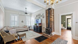 A spacious living room with hardwood floors, a fireplace, a chandelier, and a sofa.