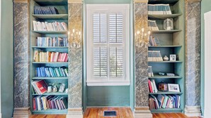 A library with marble columns, wooden flooring, and bookshelves filled with books.