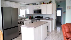 A kitchen with white cabinets, stainless steel appliances, and a central island. - Casa Key Lime  VO291 Bring your boat (Cudjoe Key)