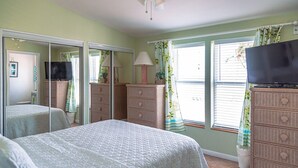 A bedroom with a bed, a television, a dresser, a mirror, and a window with curtains. - Casa Key Lime  VO291 Bring your boat (Cudjoe Key)