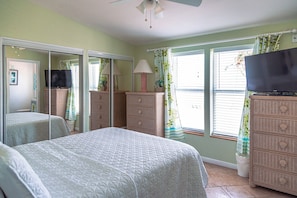 A bedroom with a bed, a television, a dresser, a mirror, and a window with curtains. - Casa Key Lime VO291 Bring your boat (Cudjoe Key)