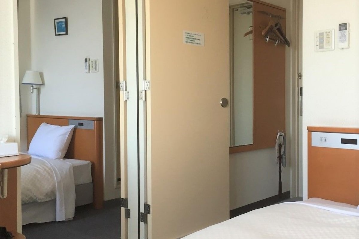 A hotel room with a bed, a bedside table, a lamp, and a mirror.