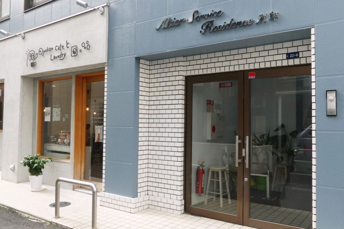 A building with a sign for 'After Service Residence 22-6' and a 'Yakon Cafe Laundry' sign.