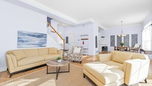 Un salon spacieux avec un canapé beige, un fauteuil à motifs et une table basse.