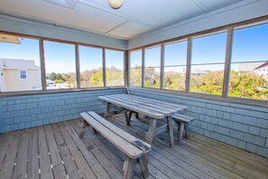 Eine überdachte Terrasse mit Holzbanken und großen Fenstern.
