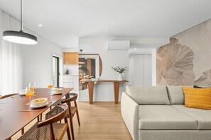 Ein modernes Wohnzimmer mit Essbereich, einer Couch und einem Tisch, der für eine Mahlzeit gedeckt ist.