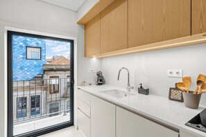 Eine moderne Küche mit weißen Schränken, einem großen Fenster und Blick auf Gebäude.