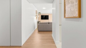 A hallway with a sofa, a flat-screen TV, and a framed artwork on the wall. - Urban Comfort @ Bonfim Boutique Flats (Porto)