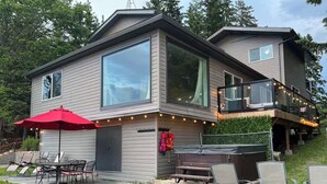 Une maison moderne à deux étages dotée d’une grande terrasse, d’un espace salon extérieur et d’un jacuzzi.