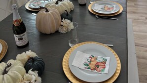 Une table à manger dressée avec des assiettes, des verres et des citrouilles, ainsi qu’une bouteille de vin Martini & Rossi.