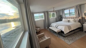 Une chambre d’hôtel moderne dotée d’un grand lit, d’un coin salon et d’une vue sur une rivière.