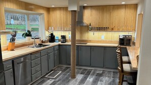Une cuisine moderne avec des meubles gris, un plan de travail en bois et une cuisinière intégrée.