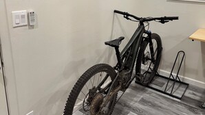 Une pièce avec un décor mural en bois, un vélo et une fenêtre avec des stores.