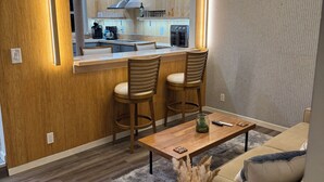 Une cuisine moderne avec des meubles en bois, un four encastré et un coin repas comprenant une table et des chaises en bois.