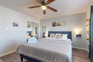 A neatly made bed with a patterned bedspread, a ceiling fan, and wall-mounted artwork. - No.7: King bed, 1bd/1ba, UNM (Albuquerque)