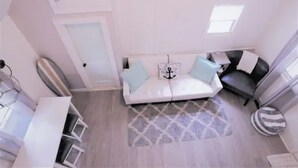 Een moderne woonkamer met een witte bank, een kamerbreed tapijt en een klein raam.