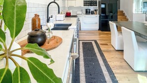 A modern kitchen with white cabinets, a black refrigerator, and a wooden countertop. - 2BD/2BA Palisades Townhouse Monthly Rental (Los Angeles)
