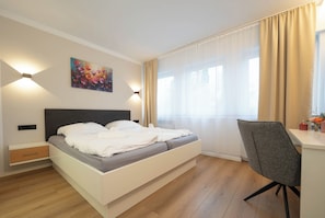 Un dormitorio moderno con una cama, mesitas de noche, un escritorio y una silla.