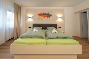 Una cama doble con ropa de cama verde, dos mesitas de noche, un cabecero y un cuadro en la pared.