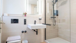 Une salle de bain moderne avec une douche à parois de verre, un lavabo blanc et des toilettes.