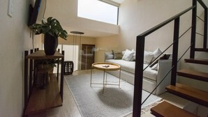 Ein modernes Wohnzimmer mit Treppe, Essbereich und einem großen Fenster, das natürliches Licht hereinlässt.