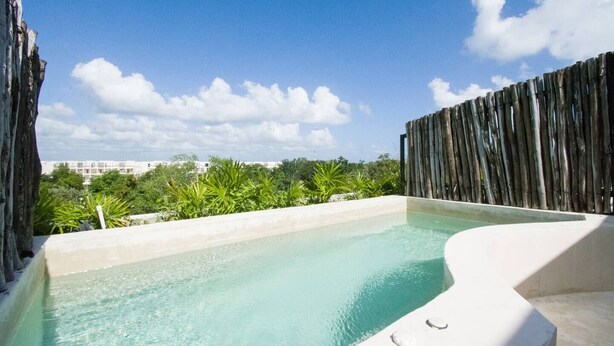 Ein Pool mit Infinity-Kante auf dem Dach, mit freier Sicht auf den Himmel und die umliegende Bepflanzung.