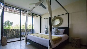 Ein Schlafzimmer mit einem Himmelbett, einem großen Spiegel und einem Balkon mit Blick auf Grünflächen.