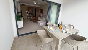 Un espace repas avec une table dressée pour quatre personnes, des chaises et un buffet garni de plats et de boissons.