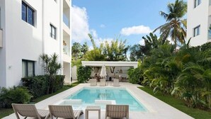 Un espace piscine avec des chaises longues et un coin salon abrité.