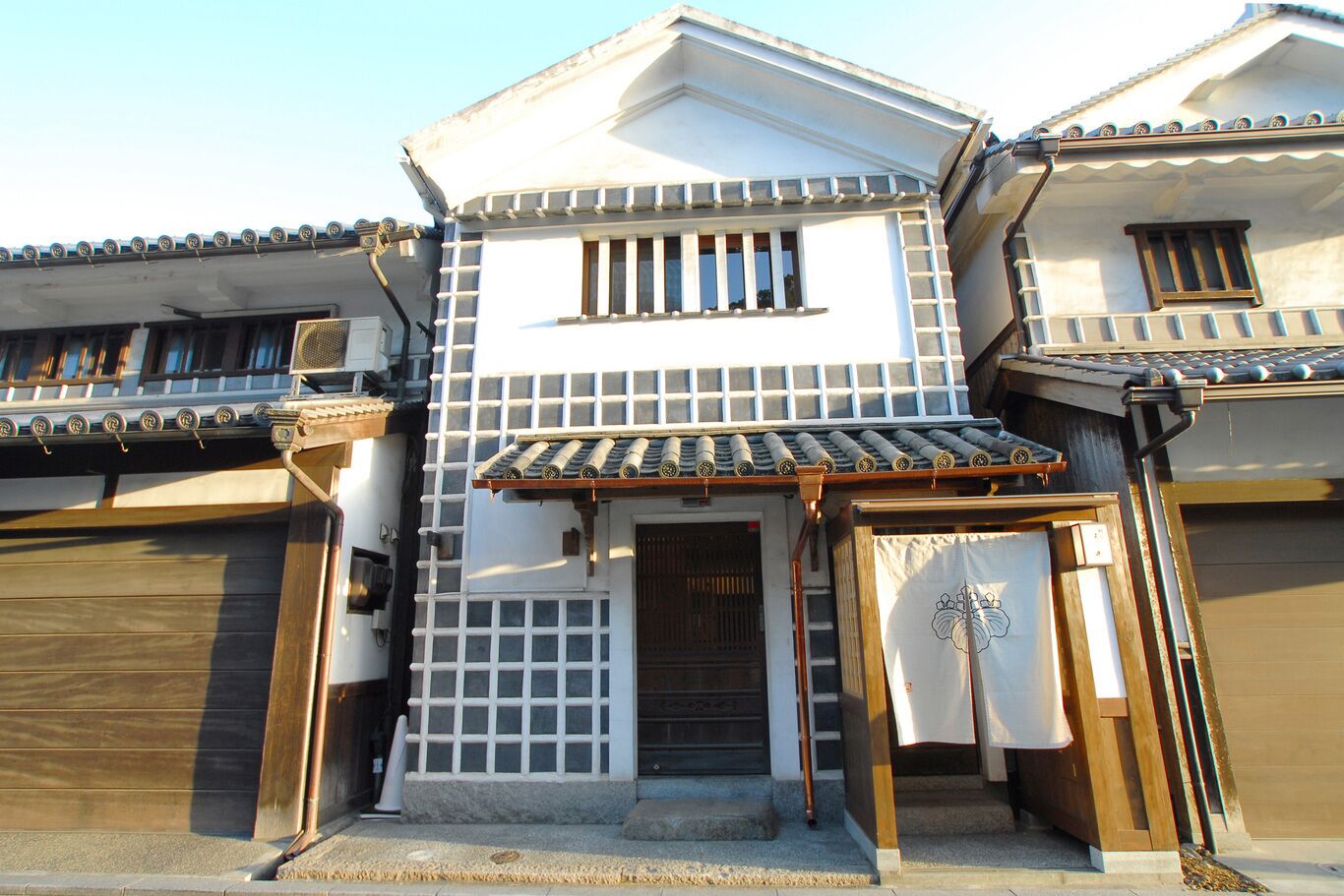 Een traditionele Japanse woning met pannendak, houten poort en klein terras.