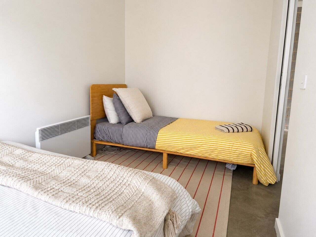 A bedroom with a bed, a smaller bed, and a radiator.