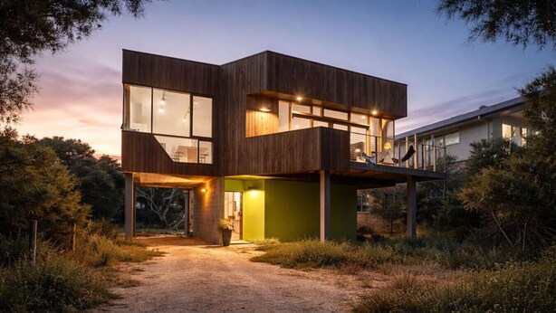 Une maison moderne à deux étages, dotée de grandes fenêtres et d’une entrée bien visible.