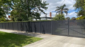 A concrete pathway leading to a black fence.
